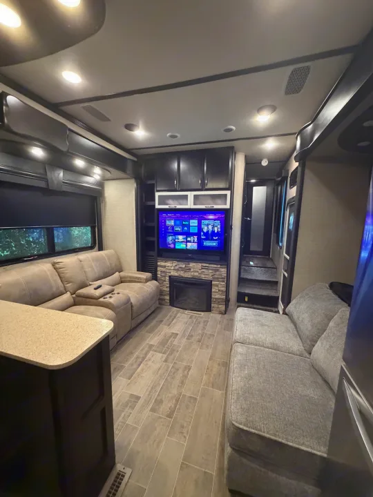 Modern RV rental living area: smart TV, fireplace, comfortable sofas, and kitchen counter. Relax in comfort on your journey.. Denali Denali Fifth Wheel 2017