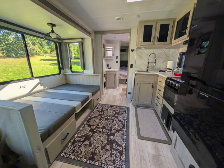 Modern rv rental interior with a fully equipped kitchen, convertible bed/seating, and scenic window views.. Forest River Alta 2850KRL 2025