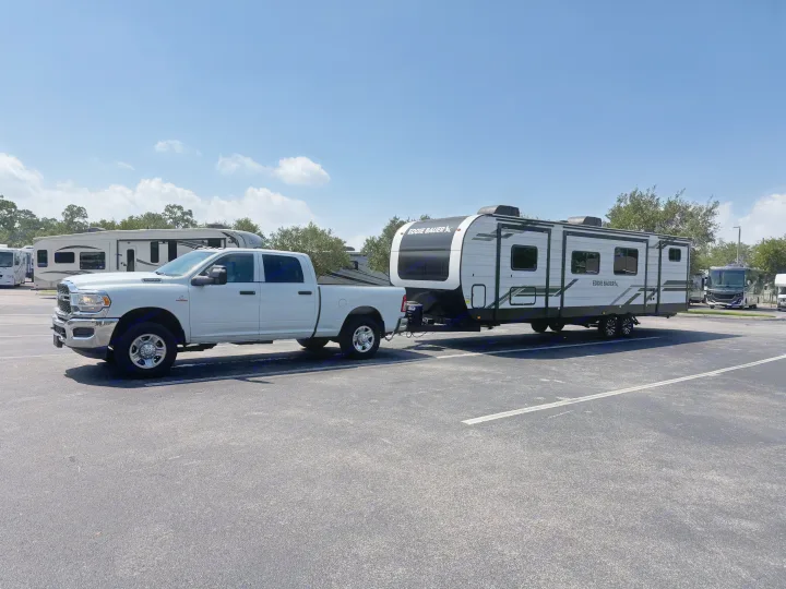 RV rental: White truck towing a modern Eddie Bauer travel trailer parked in a lot under a clear sky.. Heartland RVs Eddie Bauer 2026
