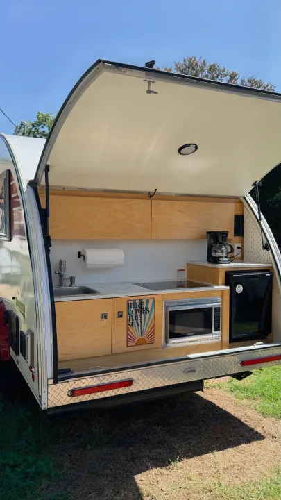 RV rental teardrop camper with its open rear galley kitchen, featuring a compact setup including a sink, microwave, and fridge.. nuCamp T@B 2022