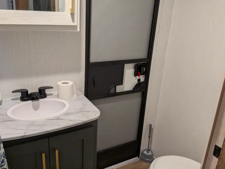 RV rental bathroom featuring a modern vanity with sink, black faucet, toilet, and a practical screen door.. Eddie Bauer Eddie Bauer 2024
