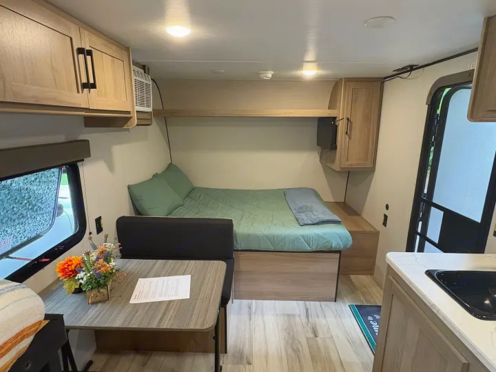 Cozy RV rental interior: comfortable bed, dinette, and compact kitchen. Perfect for travel adventures.. Keystone RV Coleman 2025