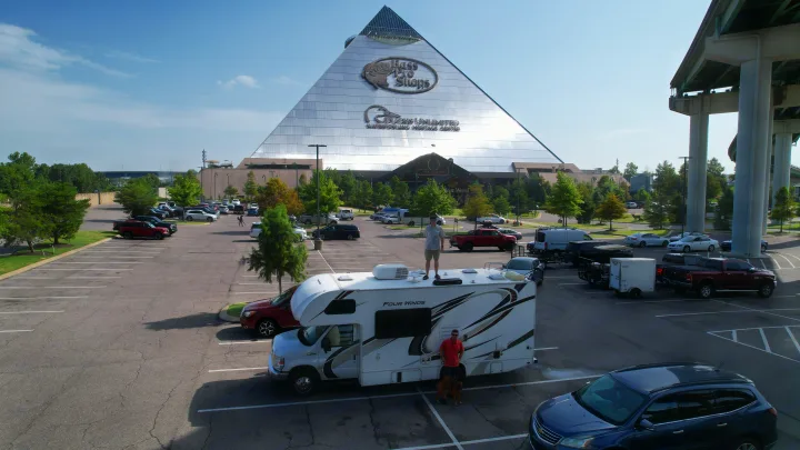 An rv rental adventure at the iconic Bass Pro Shops Memphis Pyramid. One person on the RV roof, another with a dog below.. Thor Four Winds 2020