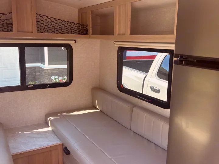 Modern RV rental interior with light wood cabinets, comfy seating, AC unit, fridge, and large windows.. Forest River Rockwood Geo Pro 2023