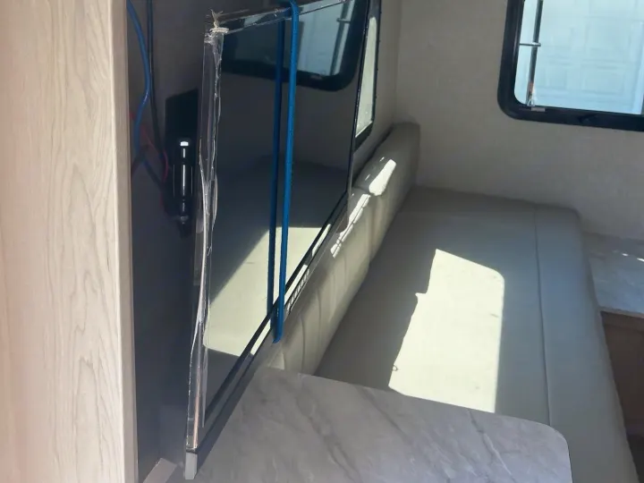Inside this **rv rental**, you see the dinette, TV, overhead cabinets, and stickers for TPMS and app controls.. Forest River Rockwood Geo Pro 2023