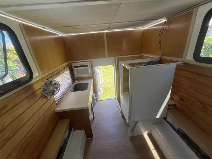 Explore this RV rental's cozy interior, featuring wood paneling, a kitchenette, AC, and bright LED strip lighting.. Ford Ford F150 2019