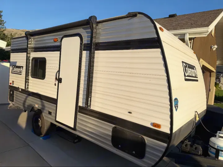 A white and black Coleman travel trailer is parked, ready for an RV rental adventure. Ideal for camping trips!. Keystone RV Coleman 2025