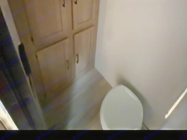 RV rental bathroom: Compact toilet and wooden storage cabinets in a dimly lit space.. Keystone RV Coleman 2025