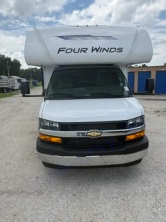 Front view of a white Four Winds RV rental, a motorhome with a Chevrolet front. Perfect for your next adventure under a cloudy sky.. Thor Four Winds 2026