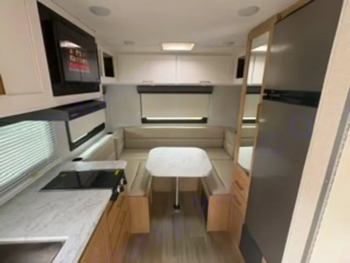 Clean RV rental interior: kitchen with microwave/stove, dining booth, and fridge. Ready for your next road trip.. Thor Four Winds 2026