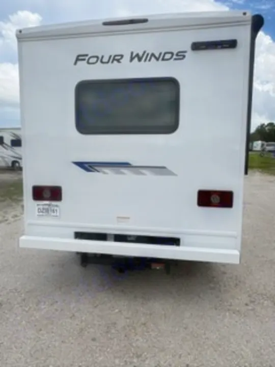 Rear view of a white Four Winds motorhome, a great RV rental option. Features include a rear window, taillights, and hitch.. Thor Four Winds 2026