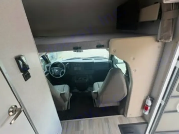 Spacious rv rental interior showing the front cab with driver and passenger seats, dashboard, and steering wheel.. Thor Four Winds 2026