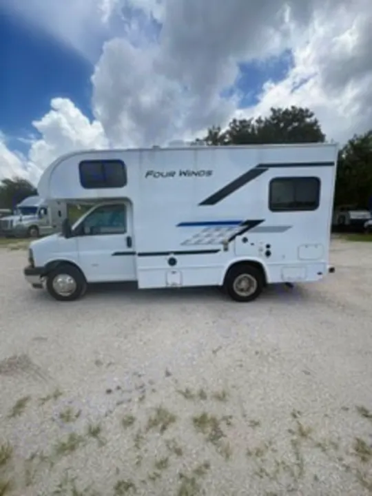 White Class C motorhome RV rental, parked on gravel under cloudy skies, ready for your next travel adventure.. Thor Four Winds 2026