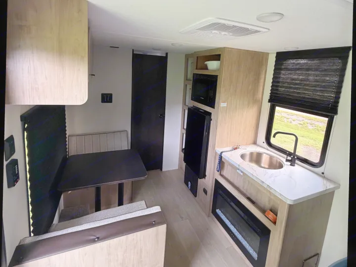 RV rental interior with a cozy dinette, modern kitchenette featuring a sink, microwave, and an electric fireplace.. Forest River Cherokee Wolf Pup 2026