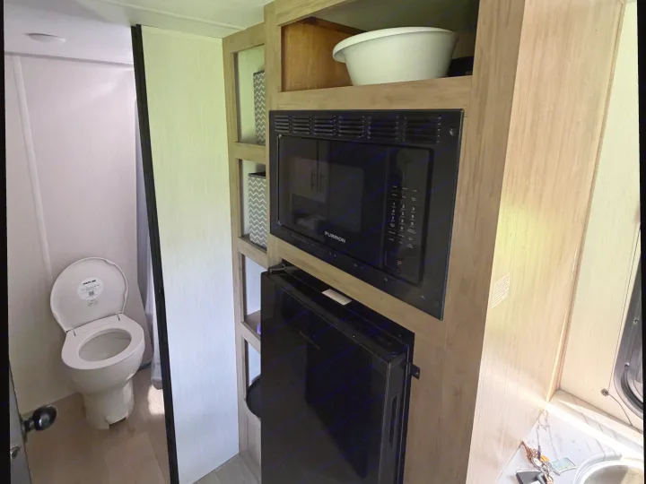 RV rental interior features a compact toilet on the left, and a kitchen unit with a microwave and fridge on the right.. Forest River Cherokee Wolf Pup 2026