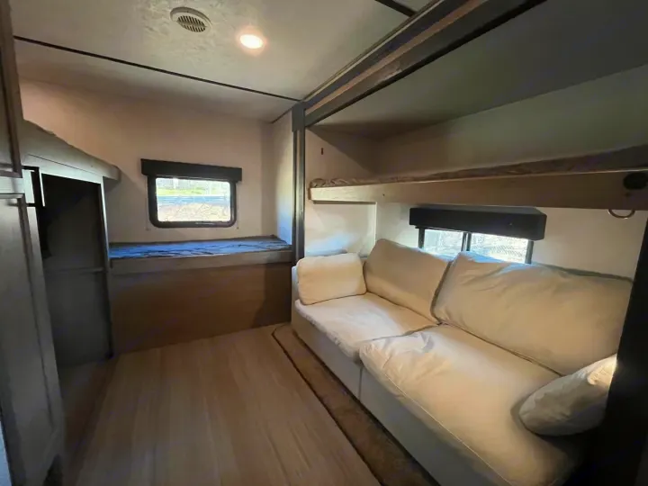 Spacious RV rental interior featuring bunk beds and a cozy white sofa, perfect for comfortable travel.. Keystone RV Hideout 2021