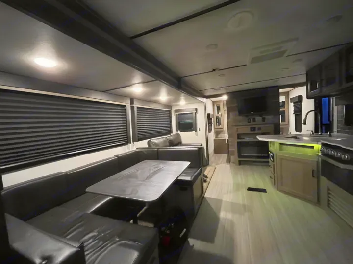 Modern RV rental interior with U-shaped dinette, kitchen, TV, and recessed lighting for a cozy feel.. Keystone RV Hideout 2021