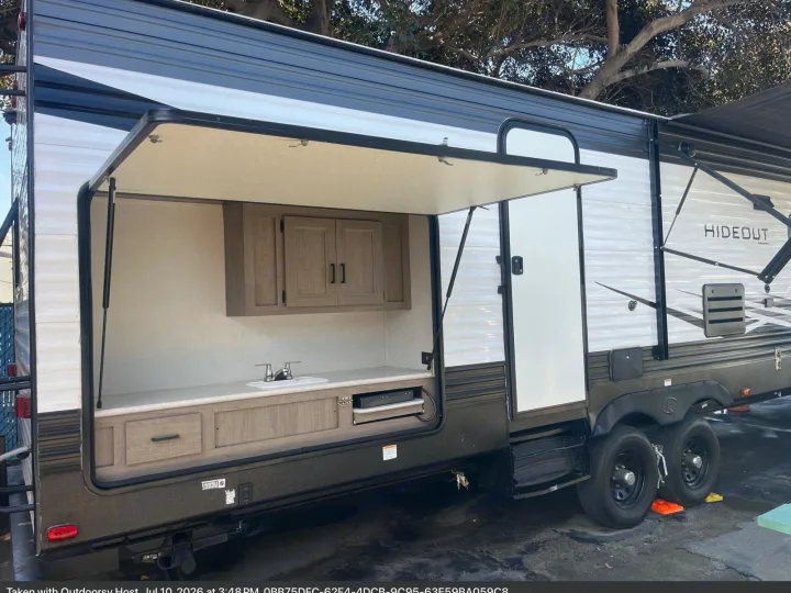 This rv rental features a convenient exterior kitchen with a sink, cabinets, and built-in cooking surface, ideal for camping.. Keystone RV Hideout 2021