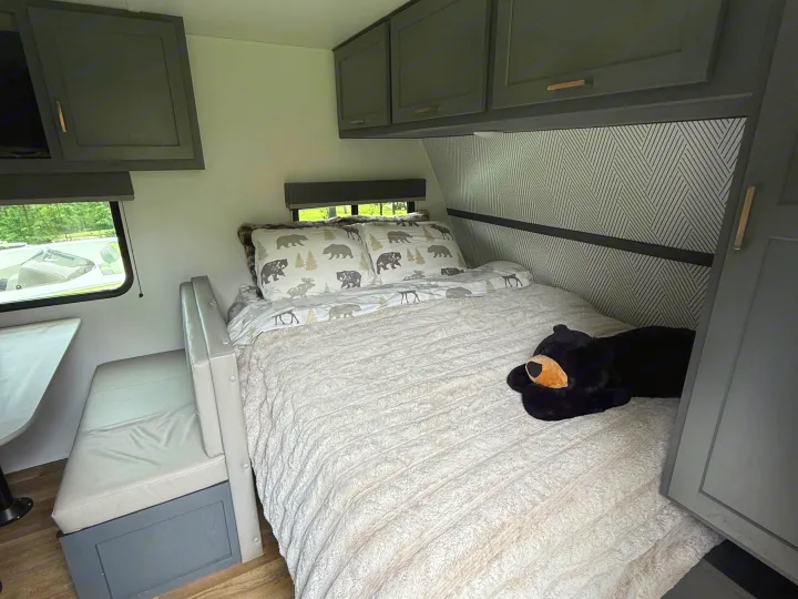 Cozy rv rental bedroom and dinette area, featuring bear-themed bedding, dark cabinets, and wood-look flooring.. Keystone RV Bullet Crossfire 2024