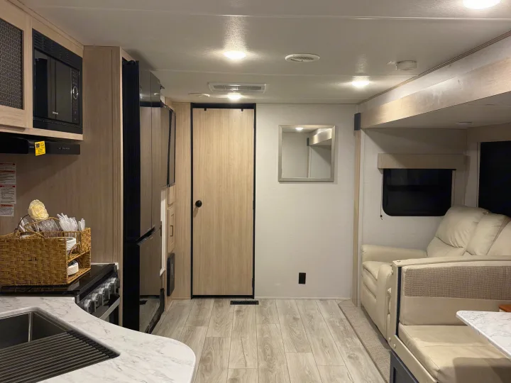 Spacious rv rental interior featuring a modern kitchen, comfortable sofa, and light-toned finishes for a pleasant travel experience.. Avenger Avenger Trailer 2025