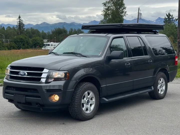 Dark gray Ford Expedition SUV with rooftop tent & all-terrain tires. An RV rental is visible in the mountain backdrop.. Ford Explorer 2016