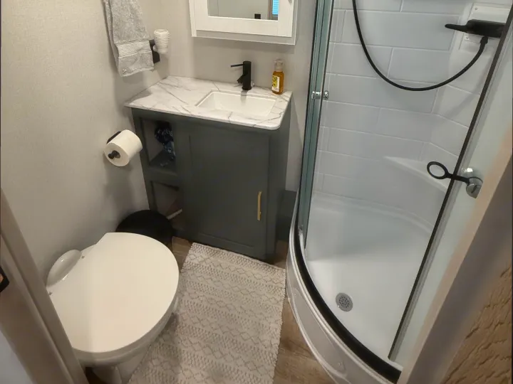 Well-appointed RV rental bathroom with a modern vanity, toilet, and glass-enclosed shower. Practical and stylish.. Heartland RVs Eddie Bauer 2026