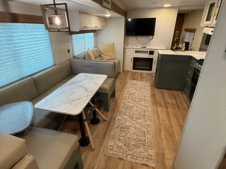 Modern RV rental interior: dinette, kitchenette, TV, and fireplace. Comfortable travel trailer living space for your adventures.. Heartland RVs Eddie Bauer 2026