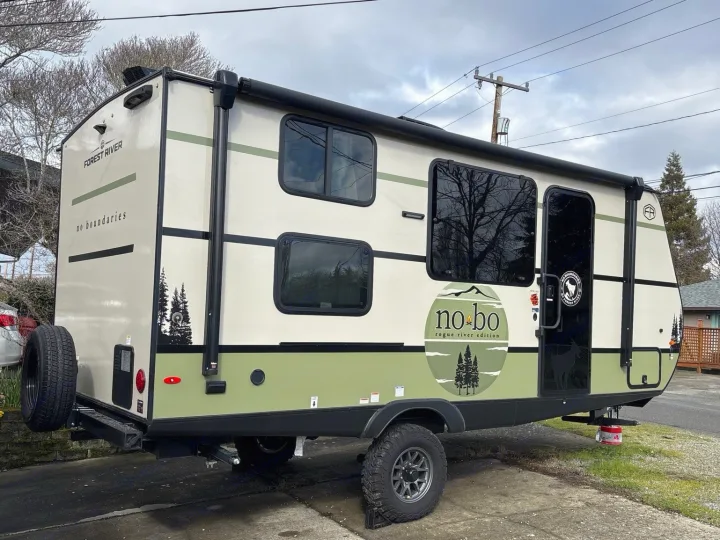 Forest River No Boundaries travel trailer: a rugged rv rental option. Features off-road tires and distinctive green graphics.. No Boundaries 18 2025