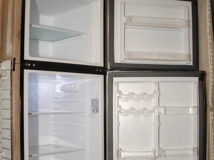 Clean, empty RV rental refrigerator and freezer, ready for your travel essentials with shelves, door bins, and egg holders.. Entegra Coach Odyssey 2020