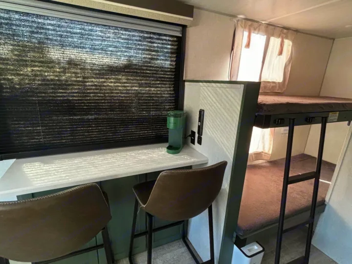 Cozy rv rental interior: modern workspace with window, two stools, and built-in bunk beds for efficient living.. No Boundaries 18 2025