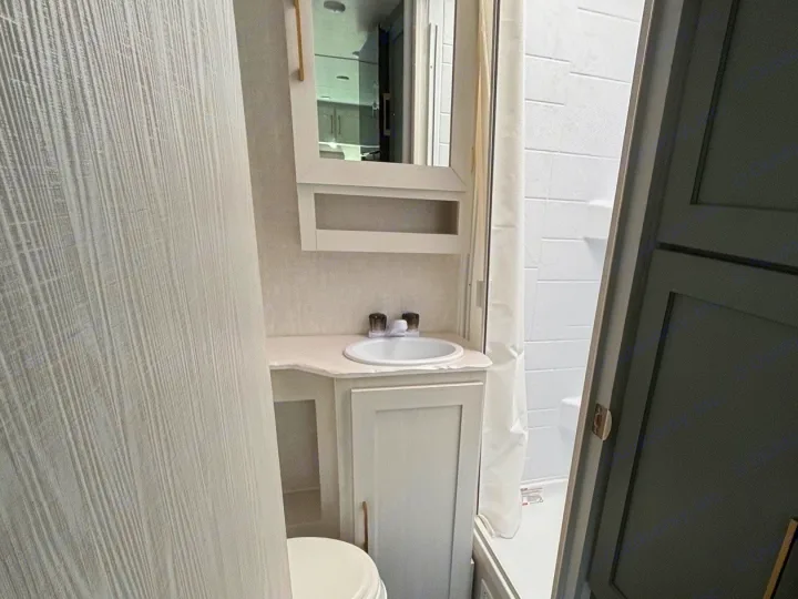 A modern, compact rv rental bathroom features a toilet, vanity with sink, mirror, and shower for comfortable travel.. No Boundaries 18 2025