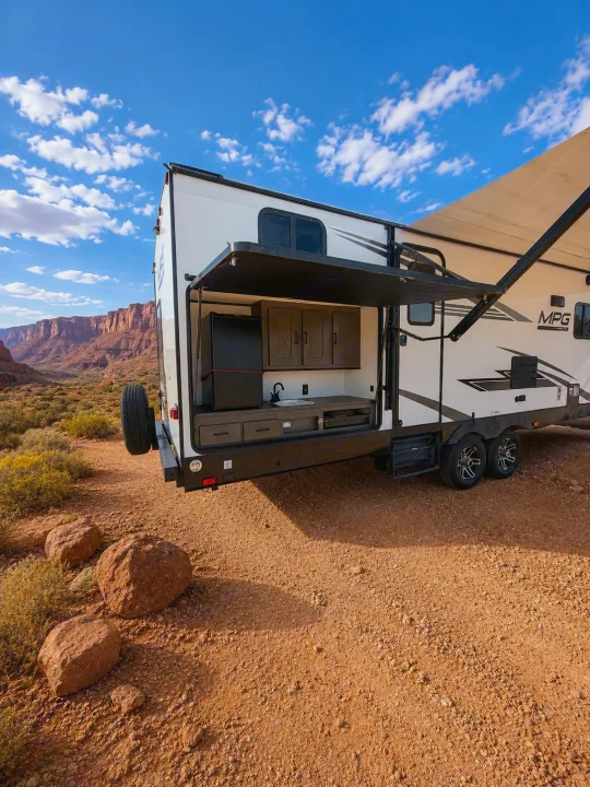 Enjoy desert adventures with this RV rental travel trailer, featuring an outdoor kitchen in a stunning red rock landscape.. Cruiser RV MPG Ultra Lite 2021