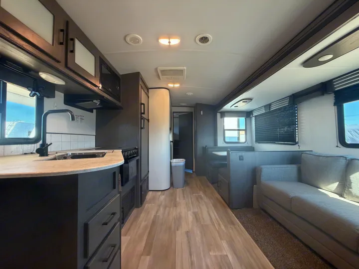 RV rental interior: full kitchen, dinette, and sofa area for comfortable travel, with wood-look flooring and dark cabinets.. Cruiser RV MPG Ultra Lite 2021