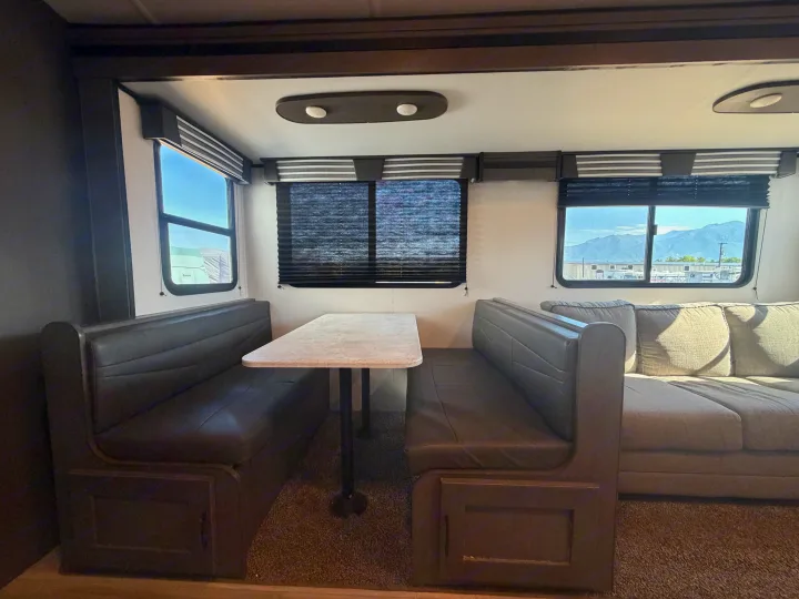 Spacious rv rental interior features a dinette with bench seats, table, and a comfortable sofa. Mountains visible outside.. Cruiser RV MPG Ultra Lite 2021