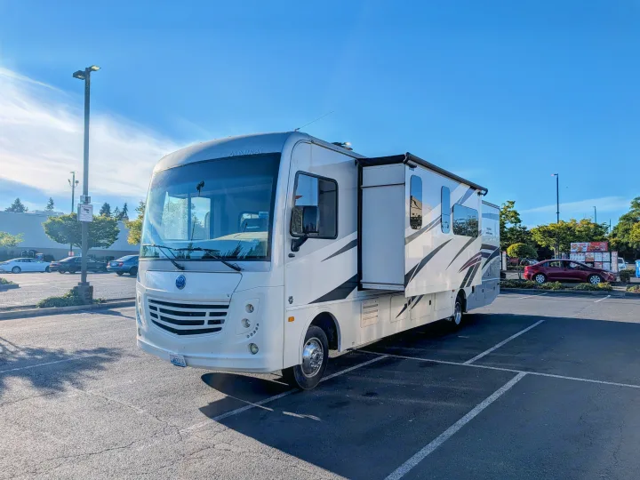 White Admiral RV rental with its slide-out extended, parked in a sunny lot. A Washington license plate CHB2216 is visible.. Holiday Rambler Admiral 2019