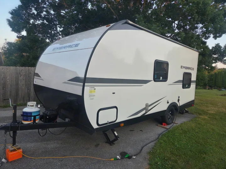 An Embrace RV rental trailer is set up with propane, power, and leveling jacks on a paved surface.. Cruiser RV Embrace 2025