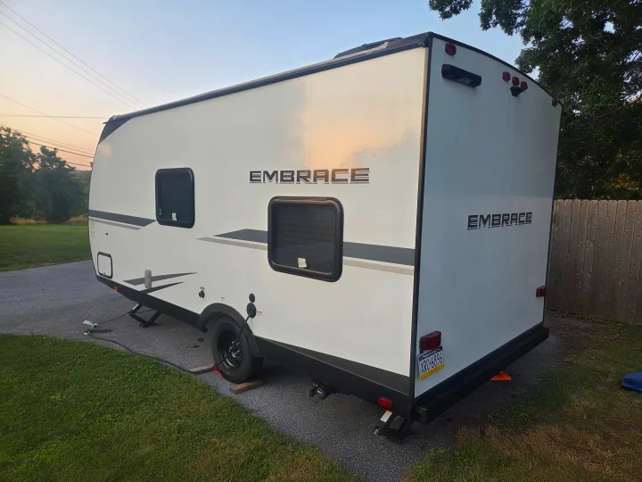 This RV rental is a white Embrace travel trailer, parked outside on an asphalt driveway next to a grassy area.. Cruiser RV Embrace 2025