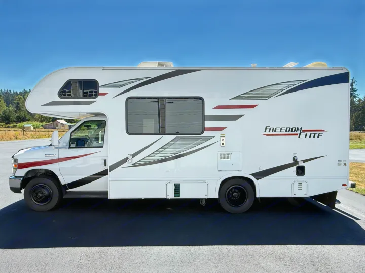 Side view of a white Class C Freedom Elite rv rental on asphalt, perfect for motorhome travel and outdoor adventures.. Thor Freedom Elite 2020