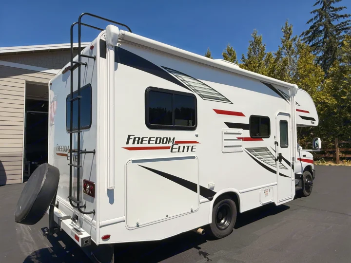 White Class C "Freedom Elite" RV rental, with awning & rear ladder, parked on a sunny day, ready for adventure.. Thor Freedom Elite 2020