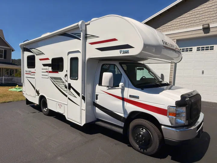 White Thor Freedom Elite Class C motorhome, perfect for your next rv rental adventure, parked on a sunny driveway.. Thor Freedom Elite 2020