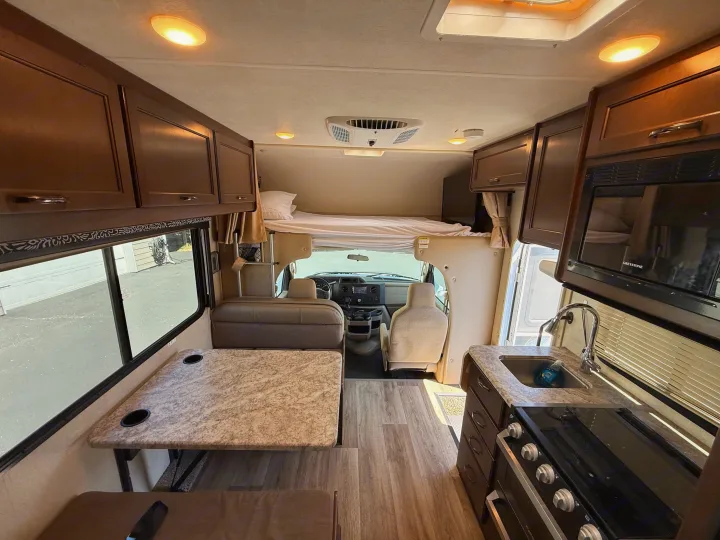 Clean rv rental interior with kitchen, dining booth, and overhead bed for comfortable travel adventures.. Thor Freedom Elite 2020