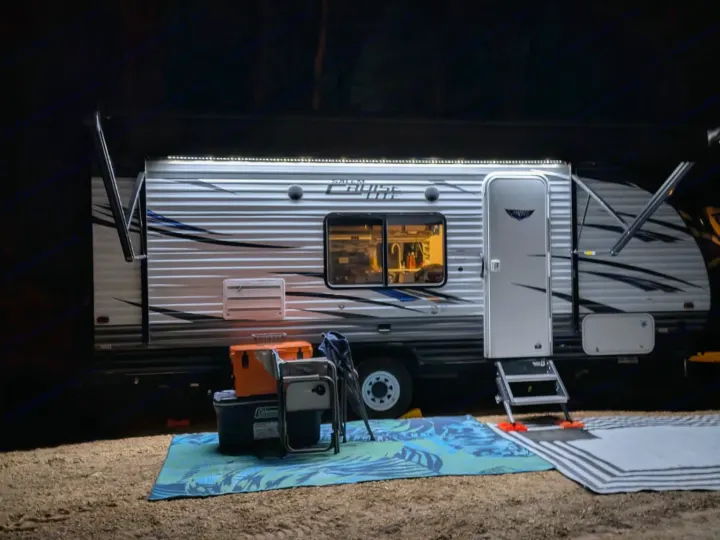 Nighttime RV rental scene: A well-lit travel trailer at a campsite, with an extended awning and illuminated ground, perfect for camping.. Forest River Salem Cruise Lite 2018