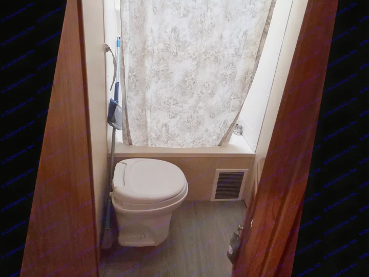 RV rental bathroom features a white toilet, patterned shower curtain, a floor vent, and a broom with dustpan.. R-Vision Trail-Lite Trail-Cruiser 2007