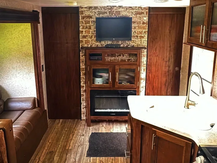 RV rental: Interior view of living area with sofa, entertainment center (TV, fireplace), and kitchen with sink/stove.. Forest River Cherokee Grey Wolf 2018