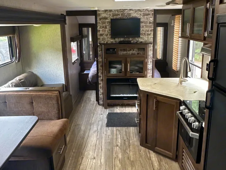 Spacious RV rental interior featuring a full kitchen, living area with sofa, entertainment center with TV & fireplace, and a bedroom.. Forest River Cherokee Grey Wolf 2018