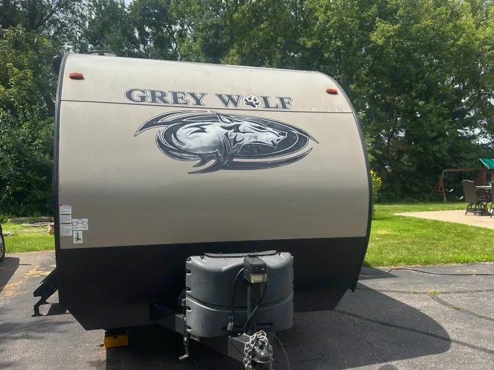 Front view of a tan and black Grey Wolf Limited travel trailer with a prominent wolf graphic. Ready for your next RV rental camping trip.. Forest River Cherokee Grey Wolf 2018