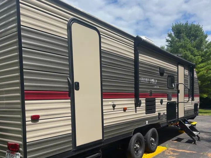 Experience the outdoors! Side view of a Grey Wolf travel trailer, an inviting RV rental with an open door & steps.. Forest River Cherokee Grey Wolf 2018