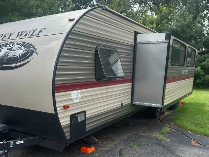 RV rental: A Grey Wolf travel trailer with an extended slide-out is parked on a driveway, supported by leveling blocks.. Forest River Cherokee Grey Wolf 2018