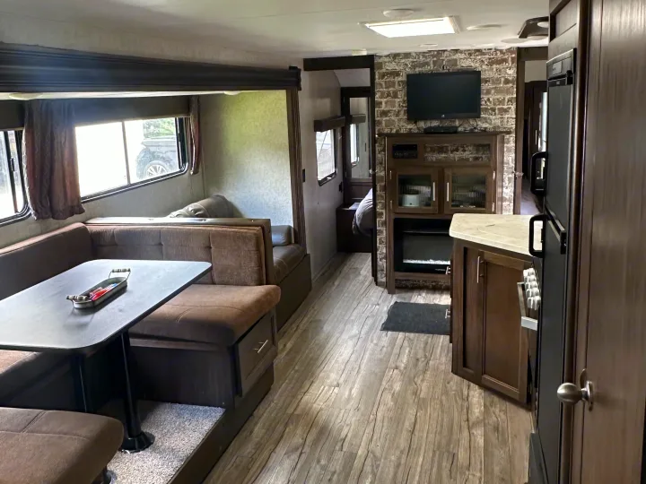 RV rental interior: modern dinette, kitchen, entertainment center with fireplace, and bedroom access. Features wood floors.. Forest River Cherokee Grey Wolf 2018