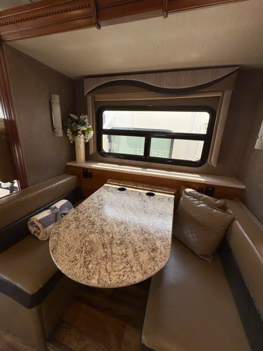 Cozy RV rental dining area with a speckled table, cushioned booth seating, and a bright window.. Jayco Precept 2017
